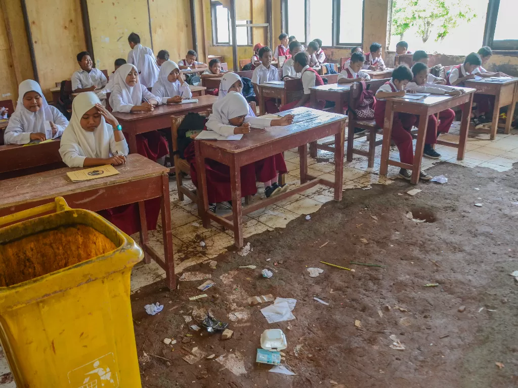 Siswa-siswi SDN (Sekolah Dasar Negeri) Samudrajaya 04 mengikuti kegiatan belajar mengajar di ruang kelas yang bagian atap rusak di daerah Tarumajaya, Kabupaten Bekasi, Jawa Barat Senin (20/1/2020). (ANTARA FOTO/Fakhri Hermansyah)