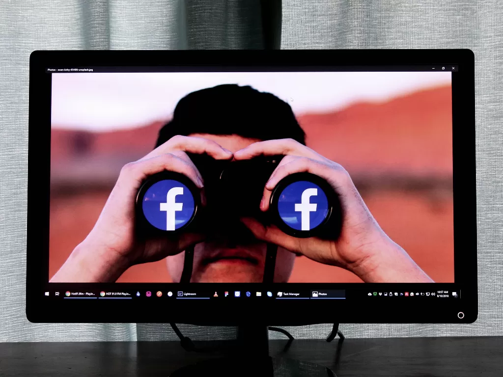 monitor yang menunjukkan pria sedang menggunakan teropong berlogo Facebook (photo/Unsplash/Glen Carrie)