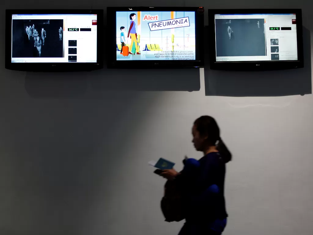 Penumpang berjalan melewati thermal scanner atau pemindai suhu tubuh saat tiba di terminal kedatangan internasional, Bandara Soekarno-Hatta, Tangerang, Banten, Selasa (21/1/2020). (REUTERS/Willy Kurniawan)