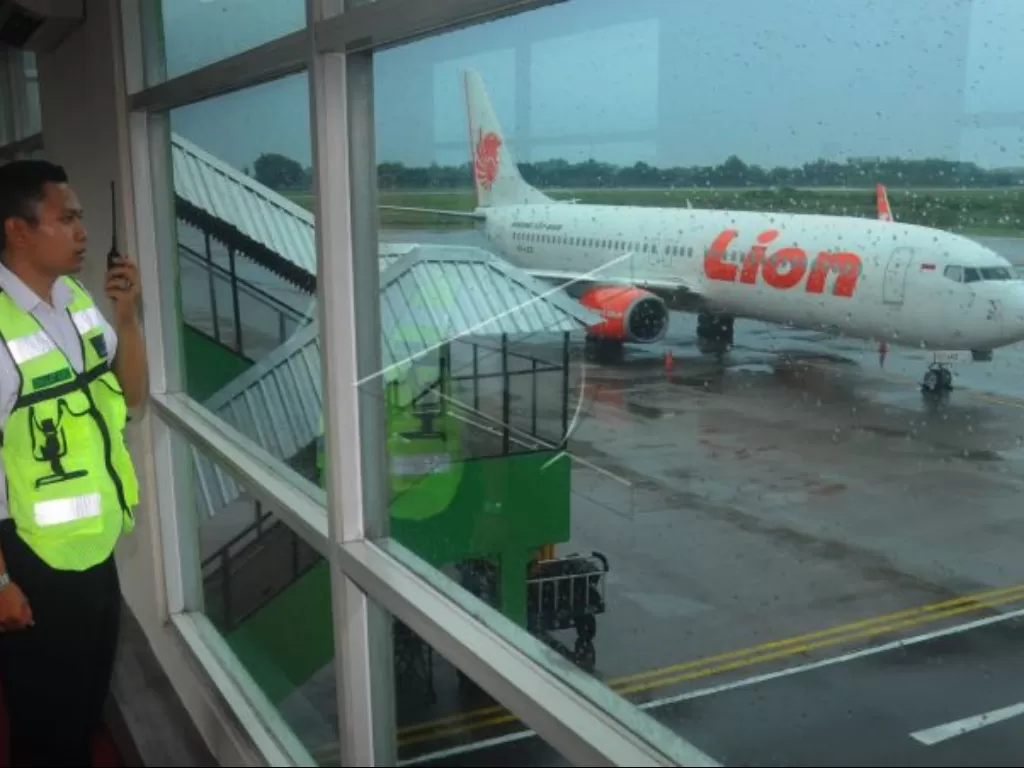 Seorang petugas bandara melakukan pemantauan keamanan di dekat pesawat komersial Lion Air saat parkir di apron Bandara Adi Soemarmo, Boyolali, Jawa Tengah. (ANTARA FOTO/Aloysius Jarot Nugroho)