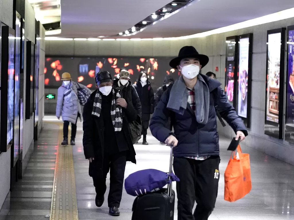 Orang-orang yang memakai topeng berjalan melalui lorong bawah tanah ke kereta bawah tanah di Beijing. (photo/REUTERS/Jason Lee)