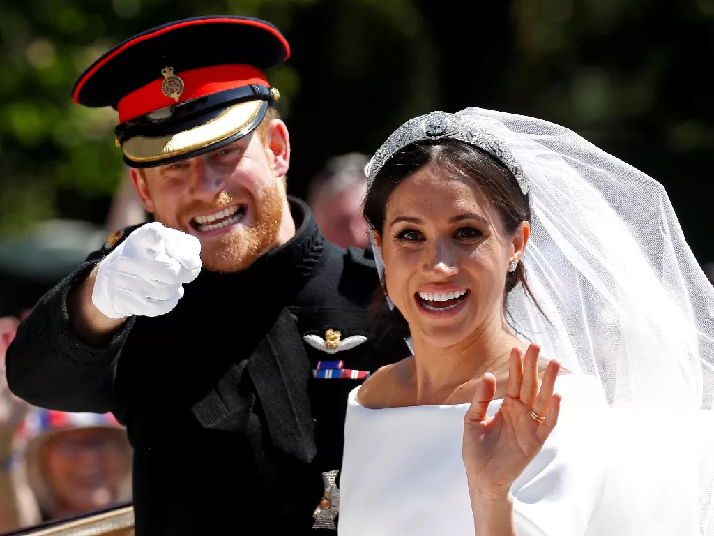 Pangeran Harry bersama istrinya Meghan ketika mereka naik kereta kuda setelah upacara pernikahan mereka di Kapel St George di Windsor Castle di Windsor, Inggris, 19 Mei 2018. (REUTERS / Damir Sagolj)