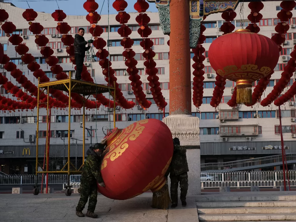 Pekerja membongkar dekorasi setelah pameran kuil untuk Tahun Baru Imlek dibatalkan di Beijing, Tiongkok, Jumat (24/1/2020). (REUTERS/Carlos Garcia Rawlins)