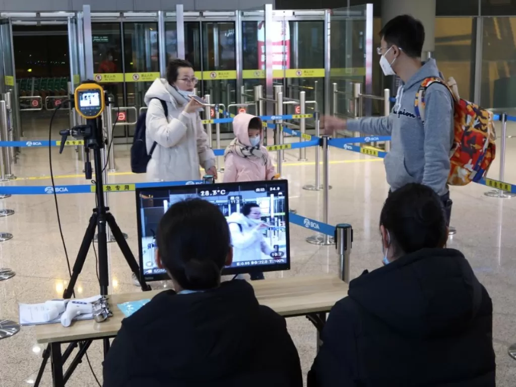 Petugas di Beijing Capital International Airport mengawasi thermal scanner, untuk mendeteksi suhu tubuh penumpang yang baru saja mendarat. (REUTERS/Martin Pollard)