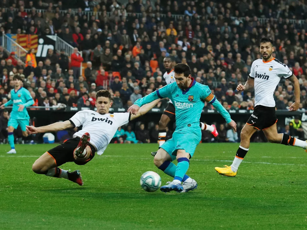 Lionel Messi sedang melewati pemain Valencia. (REUTERS/Albert Gea)