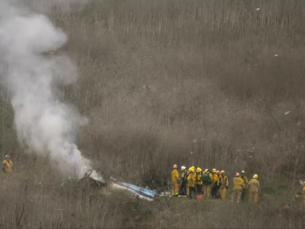 Petugas pemadam kebakaran berada di lokasi kecelakaan helikopter yang menewaskan legenda pemain basket Kobe Bryant di Calabasas, California, AS, Minggu (26/1/2020). (REUTERS/Gene Blevins)