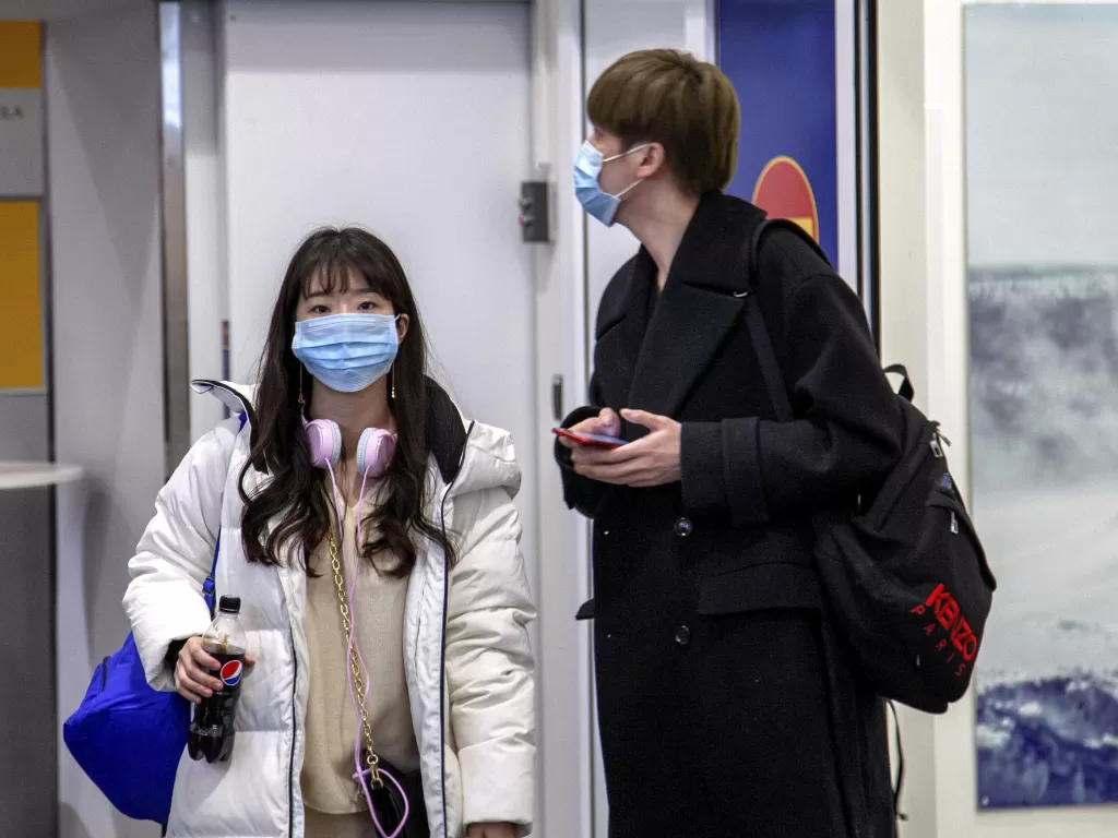 dua orang asing sedang memakai masker di bandara (photo/REUTERS/LEHTIKUVA)