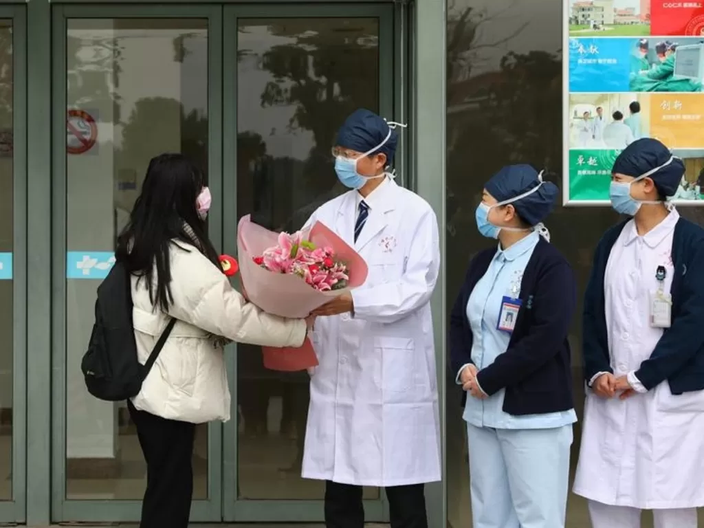 Pasien yang dinyatakan sembuh dari korona menerima karangan bunga dari dokter (shine.cn)
