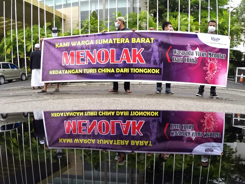 Warga tergabung dalam Forum Masyarakat Minangkabau (FMM), menggelar spanduk di halaman sebuah hotel tempat menginap turis asal Tiongkok di Padang, Rabu (29/1). (ANTARA FOTO/Iggoy el Fitra)