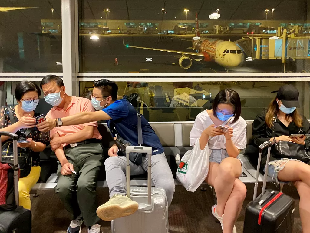 Penumpang yang mengenakan topeng menunggu untuk menaiki penerbangan mereka di Bandara Internasional Kuala Lumpur. (photo/REUTERS/Tim Chong)