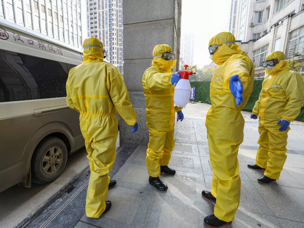 Anggota staf rumah duka dengan pakaian pelindung membantu seorang kolega dengan desinfeksi setelah mereka memindahkan mayat di rumah sakit. (photo/REUTERS/China Daily)