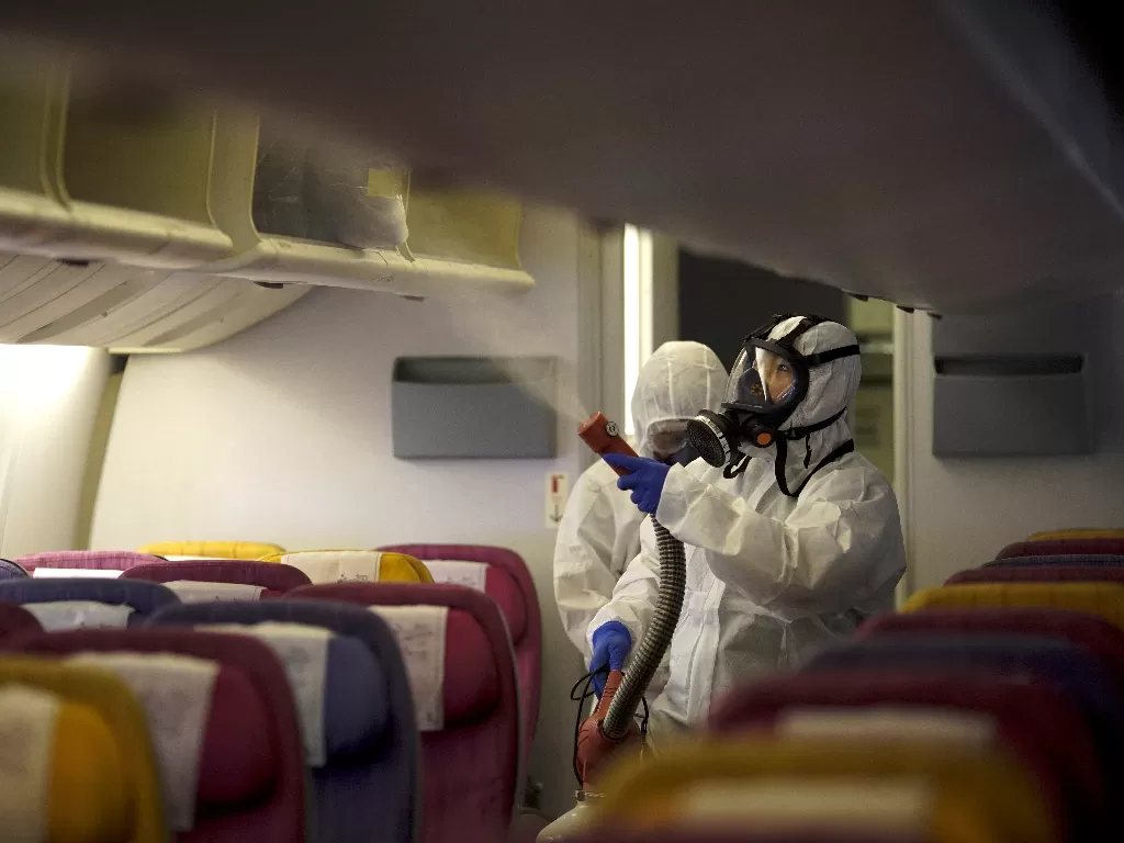 Dua orang kru Thai Airways menyemprotkan disinfektan ke kabin pesawat untuk mencegah penyebaran virus korona di Bandara Internasional Suvarnabhumi, Bangkok, Selasa (28/1). (REUTERS/Athit Perawongmetha)