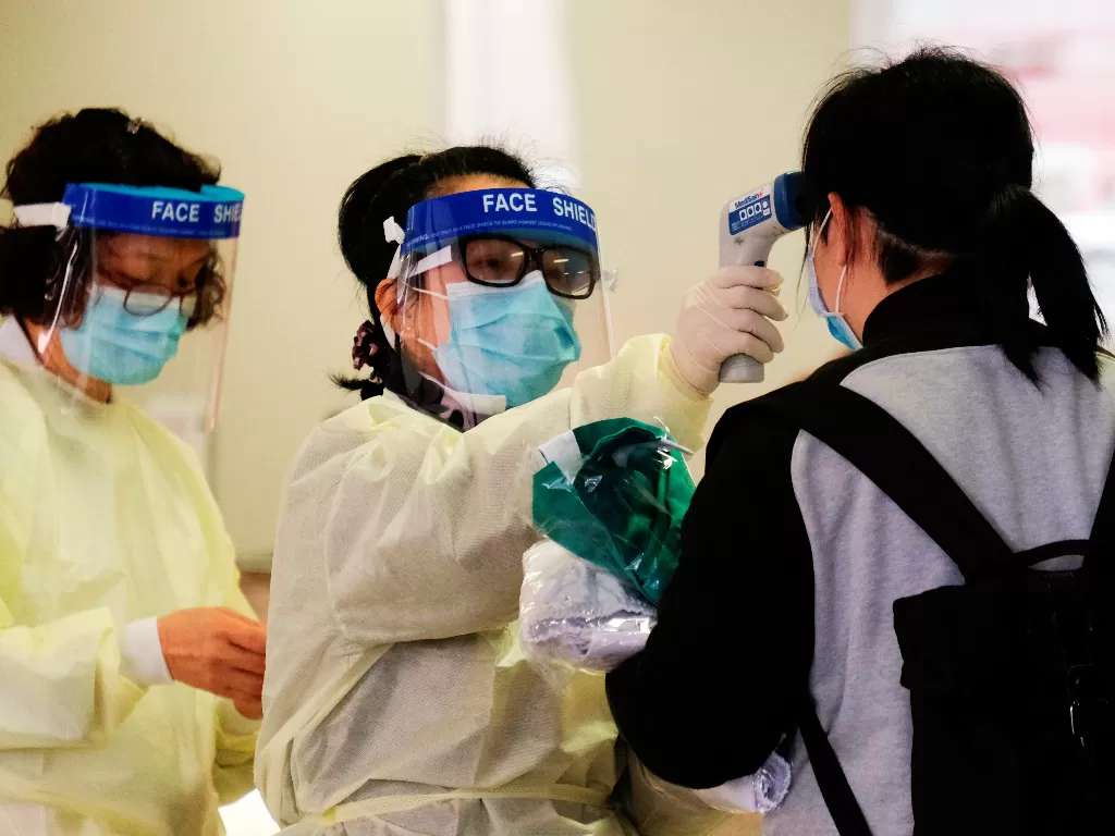 Ilustrasi: Seorang pekerja medis mengukur suhu seorang wanita dalam penerimaan Rumah Sakit Queen Elizabeth, setelah pecahnya coronavirus baru, di Hong Kong (REUTERS/Tyrone Siu)