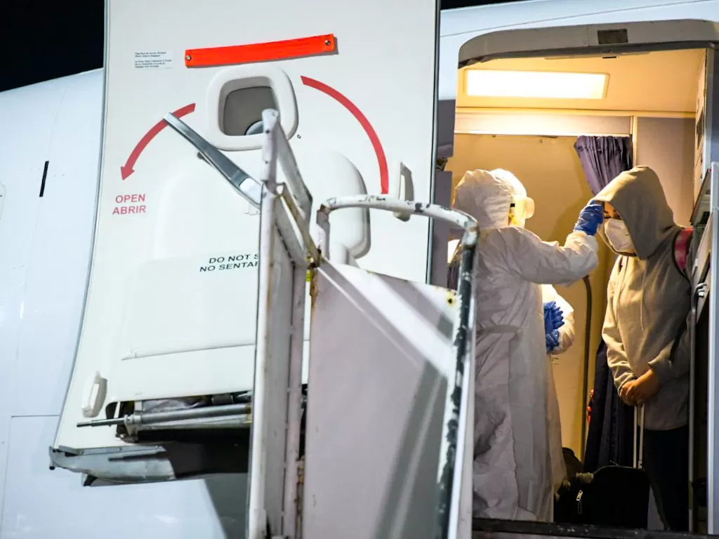 Potret penumpang tengah diperiksa oleh petugas guna melihat kondisi kesehatan (REUTERS/Press Secretariat of El Salvador Government)