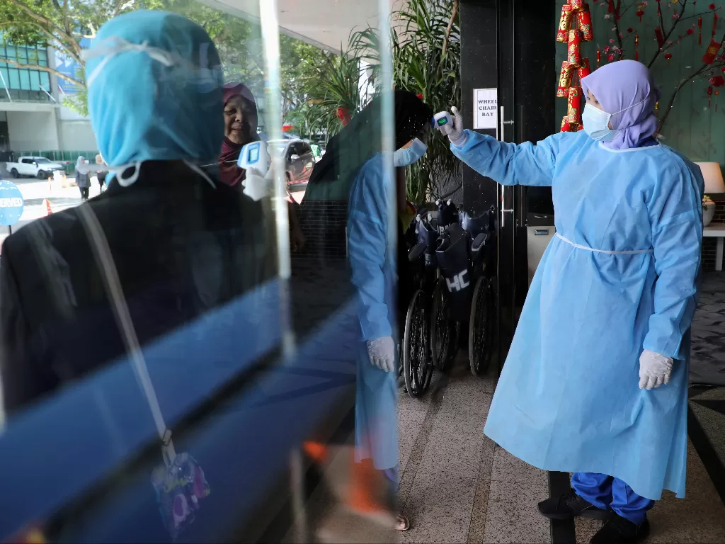 Seorang perawat memeriksa suhu pengunjung sebagai bagian dari prosedur skrining virus corona di sebuah rumah sakit di Kuala Lumpur. (photo/REUTERS/Lim Huey Teng)