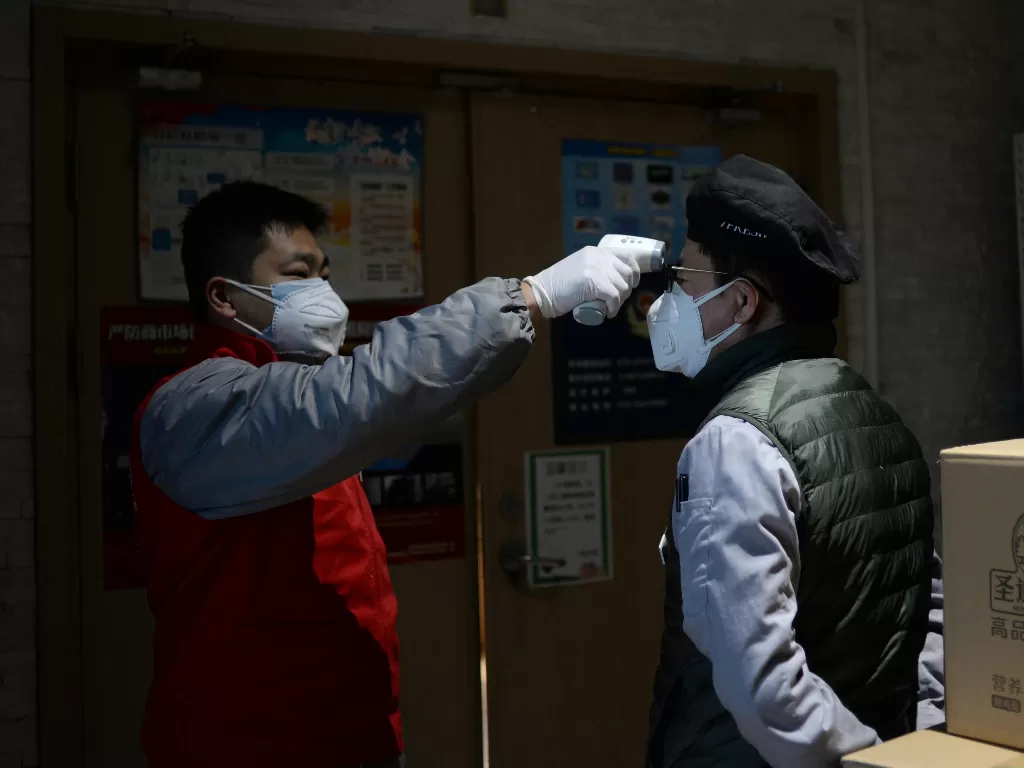Anggota staf mengecek suhu staf sebelum toko dibuka di Beijing. (photo/REUTERS/Tingshu Wang)