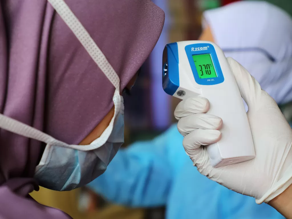 Ilustrasi: Seorang perawat memeriksa suhu pengunjung sebagai bagian dari prosedur skrining virus korona (REUTERS/Lim Huey Teng)
