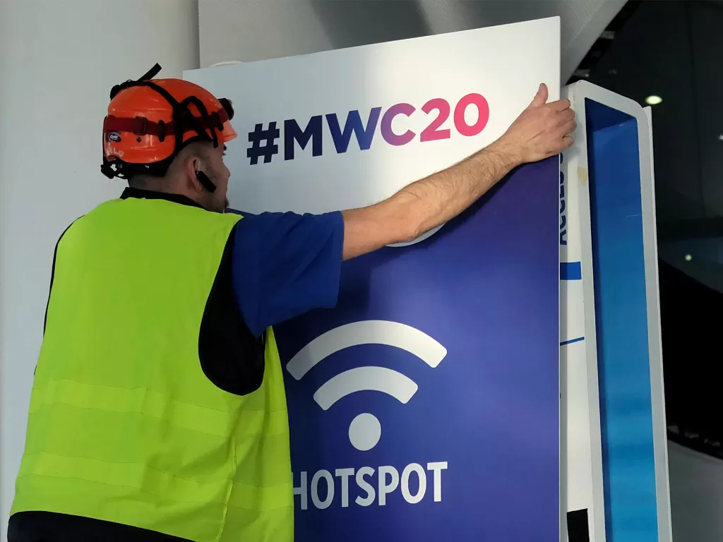 Seorang petugas sedang memasang papan poster MWC 2020 (photo/REUTERS)