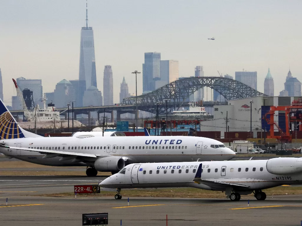 Penumpang United Airlines menerbangkan taksi dengan New York City sebagai latar belakang, di Bandara Internasional Newark Liberty, New Jersey. (photo/REUTERS/Chris Helgren)