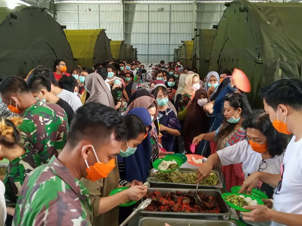 Sejumlah Warga Negara Indonesia (WNI) yang dievakuasi dari Wuhan, Tiongkok mengambil makan di pusat observasi di Hanggar Pangkalan Udara TNI AU Raden Sadjad, Ranai, Natuna, Kepulauan Riau, Rabu (12/2/2020). (ANTARA FOTO/PUSPEN TNI)