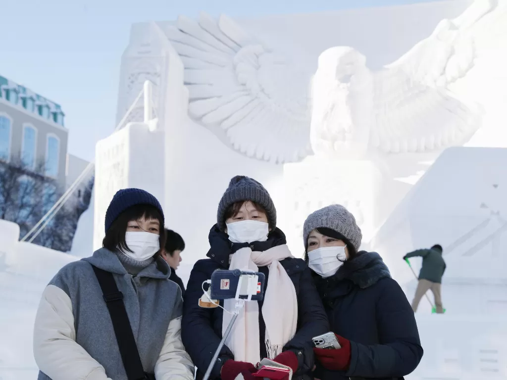 Tiga orang pengunjung berswafoto di depan salah satu patung salju di Sapporo Snow Festival, Hokaido, Jepang (4/2). (Kyodo via REUTERS)