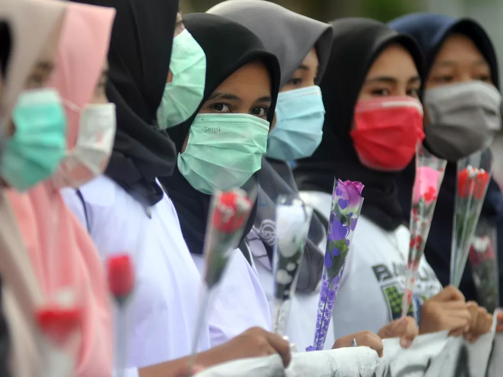 Sejumlah mahasiswi memegang bunga mawar dan menggunakan masker sambil memperlihatkan spanduk kampanye Anti Kekerasan Seksual Terhadap Perempuan, di Padang (ANTARA FOTO/Iggoy el Fitra)