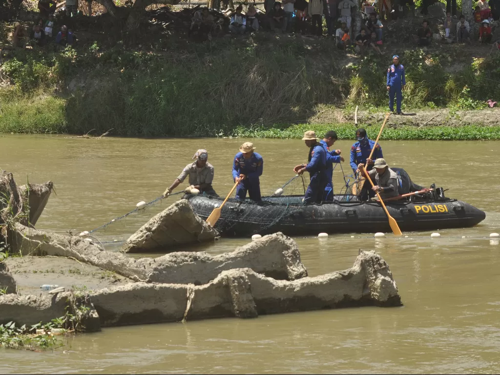 Petugas memasang jaring untuk mempersempit ruang gerak buaya liar yang terjerat ban sepeda motor saat berlangsungnya proses penyelamatan di Sungai Palu, Sulawesi Tengah, Jumat (7/2/2020). (ANTARA/Mohamad Hamzah)