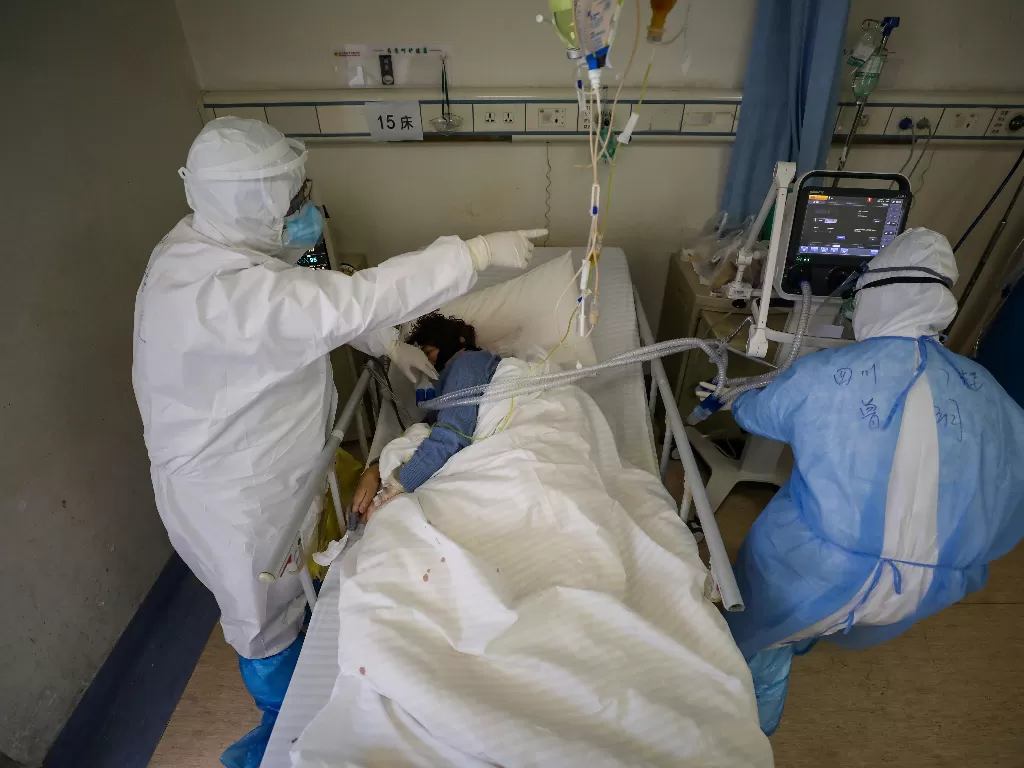 Ilustrasi: para pekerja medis dengan mengenakan pakaian pelindung memeriksa seorang pasien di dalam bangsal terisolasi Rumah Sakit Palang Merah Wuhan (China Daily via Reuters)