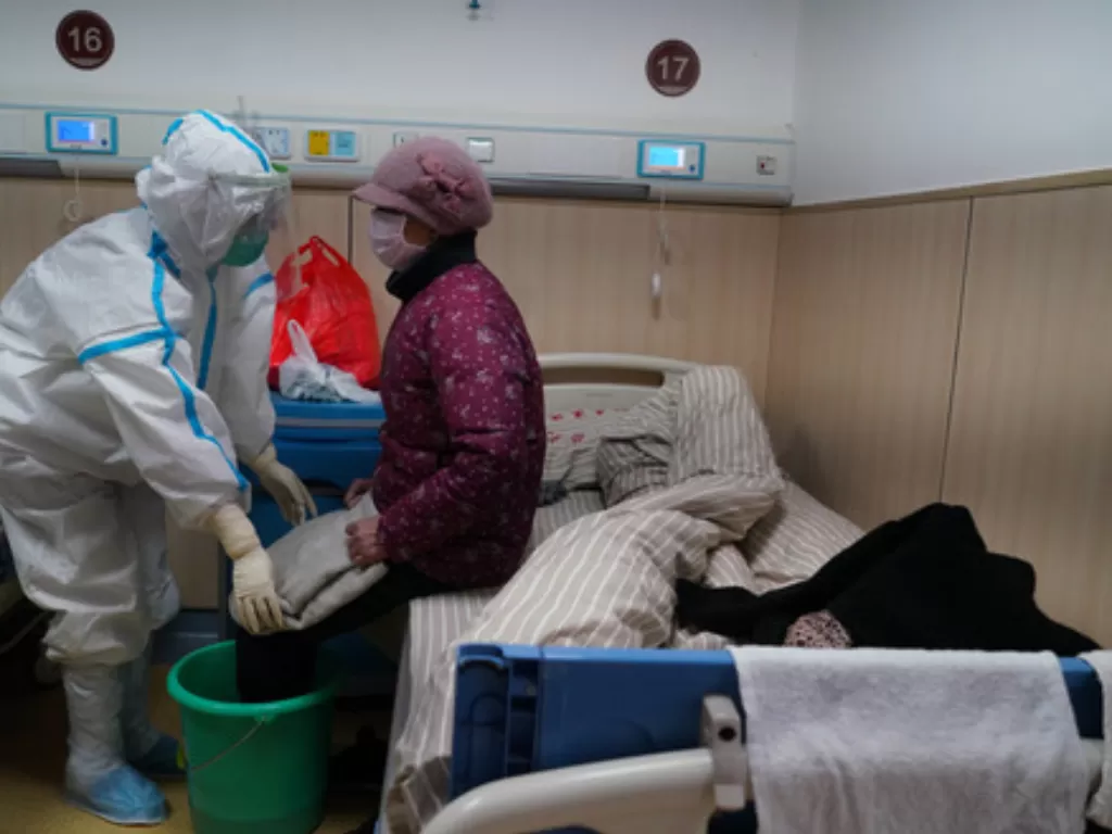 Seorang pasien menjalani perawatan rendam kaki menggunakan ember berisi ramuan obat-obatan di sebuah bangsal isolasi di RS afiliasi Universitas Pengobatan Tradisional Tiongkok Jiangxi di Nanchang, Provinsi Jiangxi, Selasa (18/2/2020). (Xinhua/Hu Chenhuan)