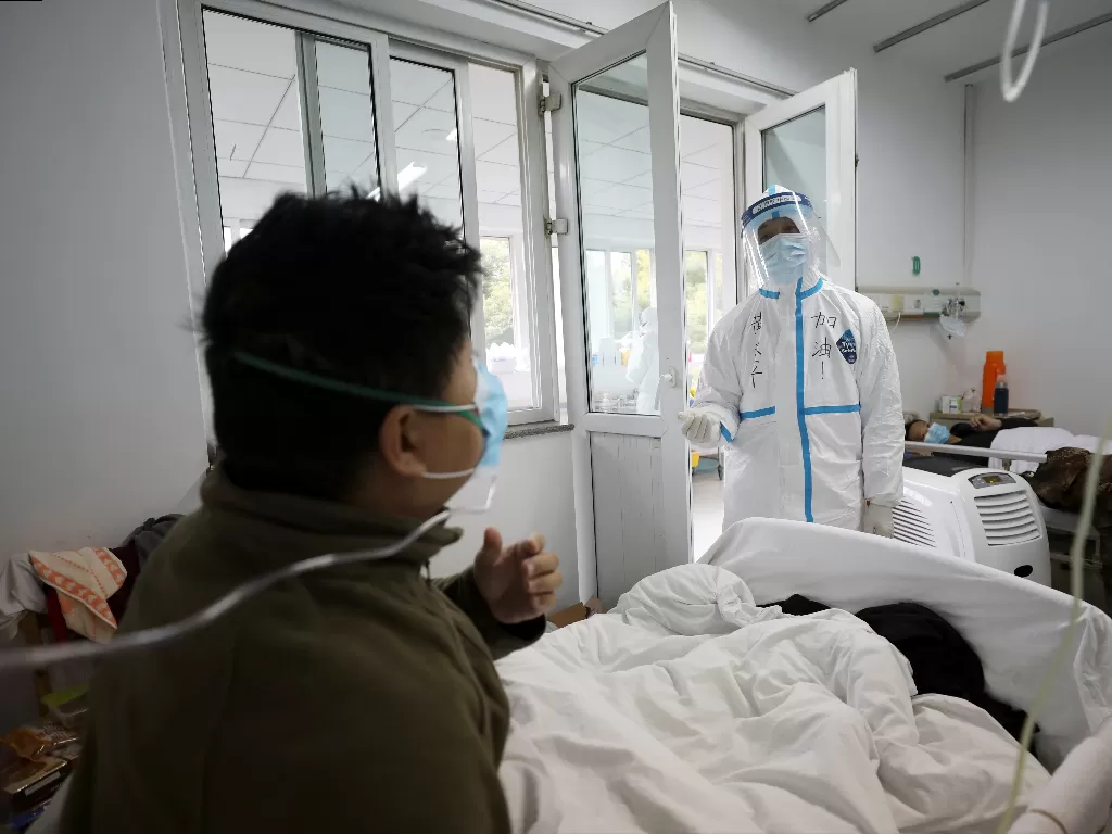 Pekerja medis dalam pakaian pelindung berinteraksi dengan pasien di dalam bangsal terisolasi di Rumah Sakit Jinyintan di Wuhan. (photo/REUTERS/China Daily)