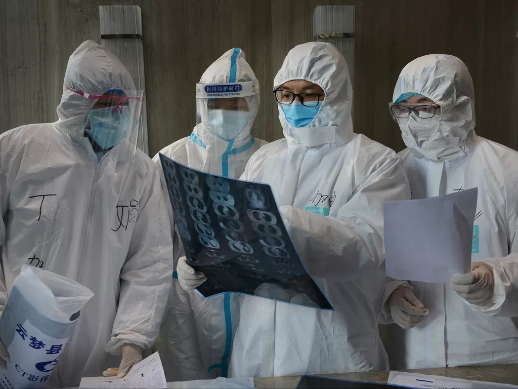 Pekerja medis dalam pakaian pelindung memeriksa gambar CT scan di rumah sakit di Yunmeng. (photo/Reuters/China Daily)