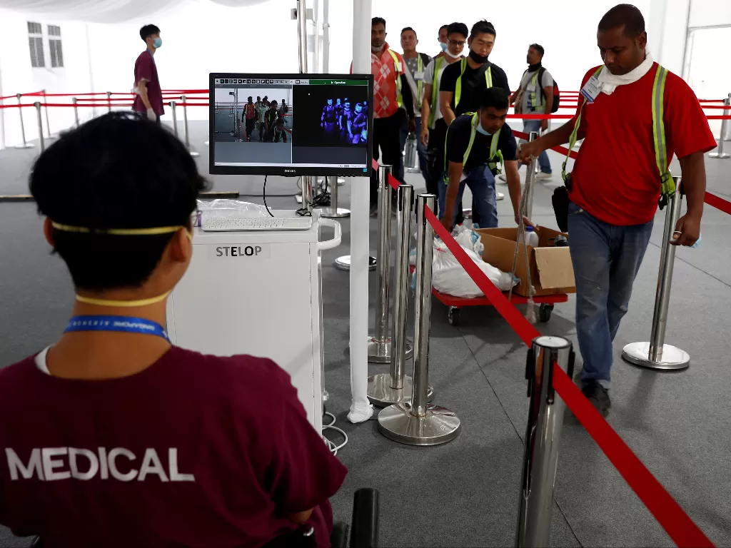 Kontraktor dan pekerja lulus pemindai termal sebagai bagian dari tindakan pencegahan penyebaran koronavirus selama pratinjau media Singapore Airshow di Singapura. (photo/REUTERS/Edgar Su)