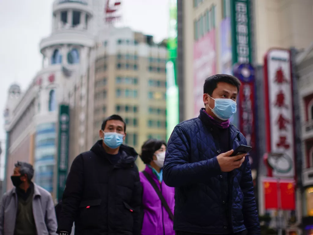Beberapa orang sedang menggunakan masker saat berjalan di luar rumah (photo/REUTERS/Aly Song)