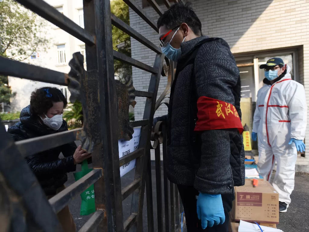 Warga memindai kode QR dengan ponselnya untuk membayar peralatan pelindung yang dibeli melalui pesanan kelompok di kompleks perumahan di Wuhan. (photo/REUTERS/China Daily)