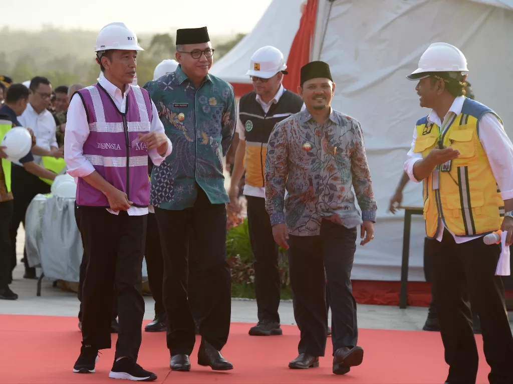 Presiden Joko Widodo (kiri) didampingi Plt Gubernur Aceh, Nova Iriansyah (kedua kiri) berjalan saat meninjau perkembangan pembangunan Seksi IV jalan tol di Desa Indra Puri, Kabupaten Aceh Besar, Aceh, Jumat (21/2/2020). (photo/ANTARA/Ampelsa)