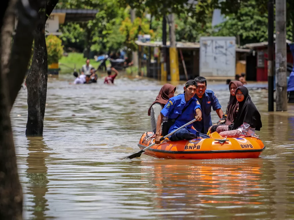 Petugas bersama warga melintasi banjir menggunakan perahu karet. (ANTARA FOTO/Fauzan)