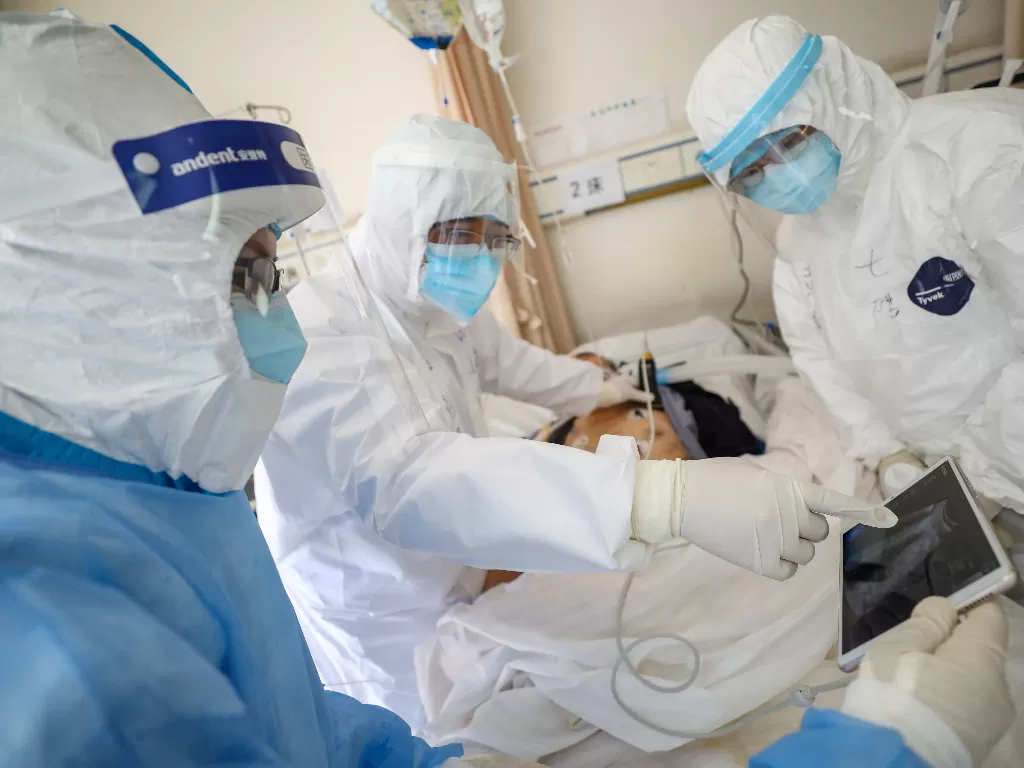 Pekerja medis yang mengenakan pakaian pelindung mendatangi seorang pasien di dalam bangsal terisolasi Rumah Sakit Palang Merah Wuhan di Wuhan, pusat wabah baru virus corona. (photo/Reuters/China Daily)