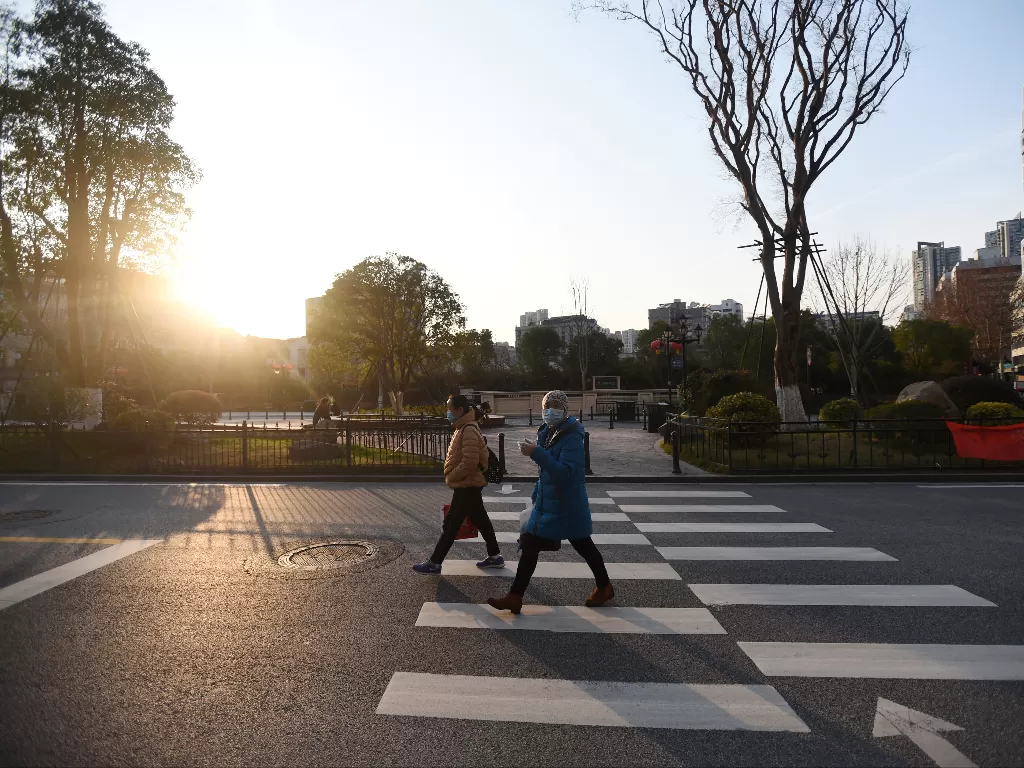 Ilustrasi - Pejalan kaki yang memakai masker berjalan di Wuhan. (photo/Reuters)