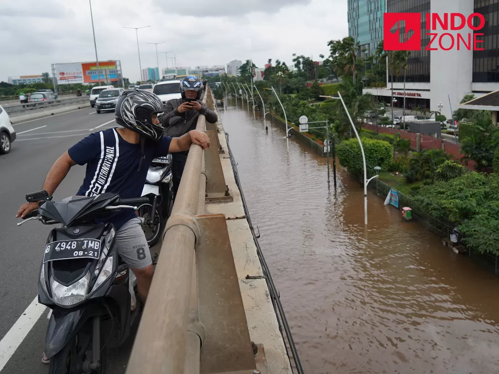Sejumlah pengendara motor mengamati banjir saat melintasi tol Wiyoto Wiyono di kawasan Pulo Mas, Jakarta, Selasa (25/2/2020). (INDOZONE/Arya Manggala)