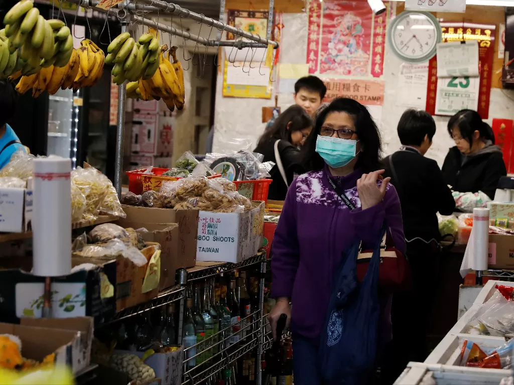 Ilustrasi - Seorang wanita memakai masker untuk berbelanja di pasar. (photo/Reuters/Shannon Stapleton)