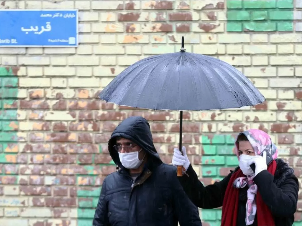 Warga Iran memakai masker pelindung saat berjalan di sebuah jalan di Kota Tehran, Iran, Selasa (25/2/2020). (photo/Reuters/Nazanin Tabatabaee)