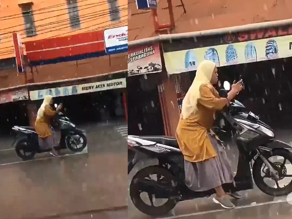 Seorang wanita bermain gawai meski sedang hujan deras. (photo/Twitter/@forzatives)