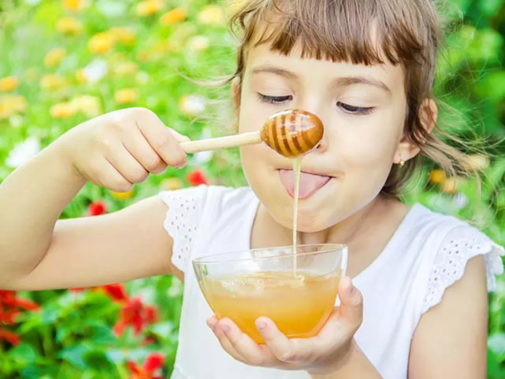 Ilustrasi anak mengonsumsi madu. (MomJunction)
