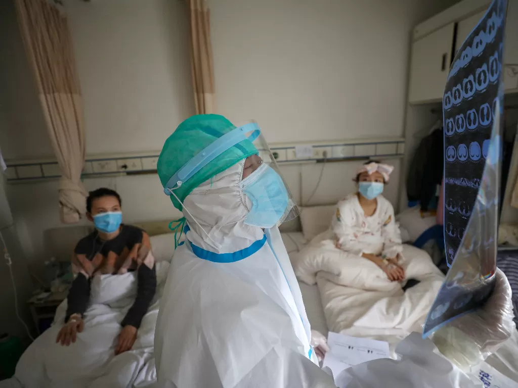 Seorang petugas kesehatan yang sedan melakukan pemeriksaan terhadap pasien corona. (photo/Reuters/China Daily)
