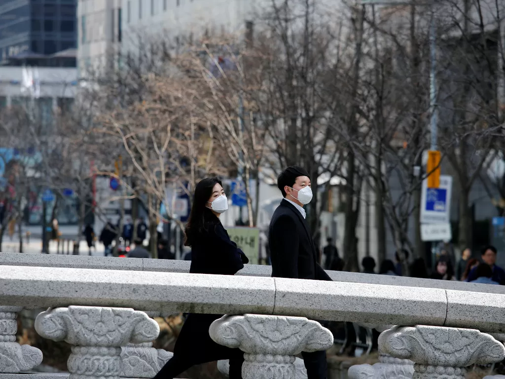 Dua orang pekerja mengenakan masker saat berjalan di sebuah jembatan di pusat kota Seoul, Korea Selatan, Senin (24/2). (REUTERS/Heo Ran)
