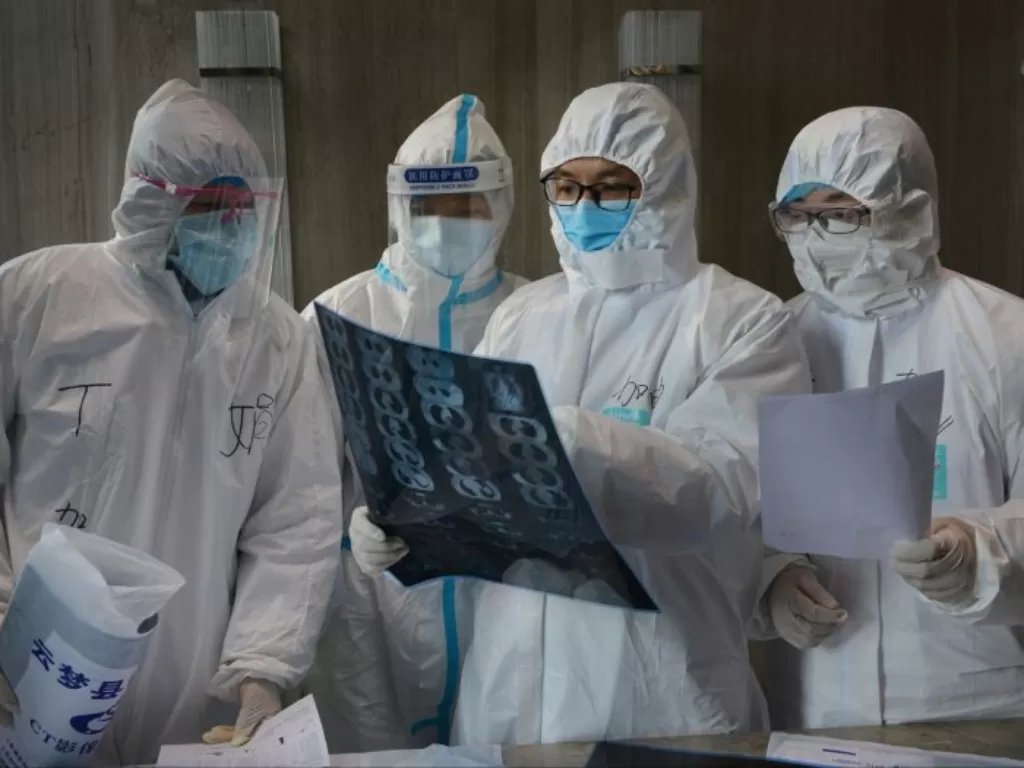 Pekerja medis dalam pakaian pelindung memeriksa gambar CT scan di rumah sakit di Yunmeng. (REUTERS/China Daily)