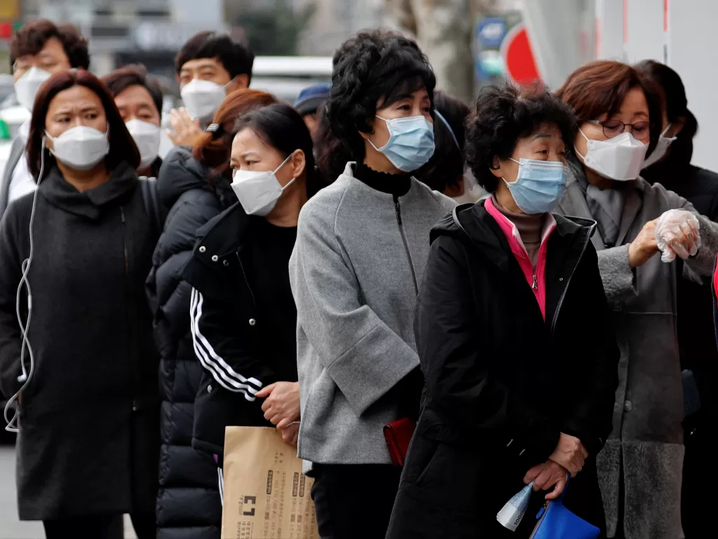 Orang-orang yang memakai topeng berdiri dalam antrean untuk membeli masker wajah di depan sebuah toko obat di tengah meningkatnya kasus penyakit coronavirus novel COVID-19 yang dikonfirmasi di Daegu. (photo/Reuters/Kim Kyung-Hoon)