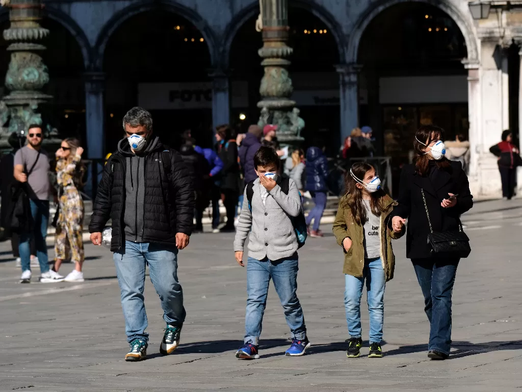 Ilustrasi: Beberapa turis tampak memakai masker saat berjalan di lapangan Santo Markus di Venesia (REUTERS/Manuel Silvestri)