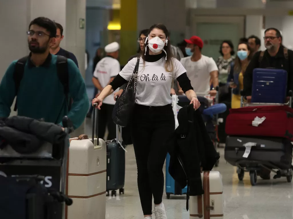 Ilustrasi warga memakai masker saat tiba di bandara untuk mencegah virus corona. (REUTERS/Amanda Perobelli)