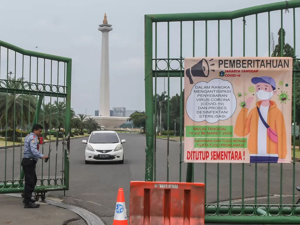 Petugas keamanan membuka pintu saat ada kendaraan yang keluar dari kawasan Monas di Jakarta, Sabtu (14/3/2020). (ANTARA FOTO/Muhammad Adimaja)